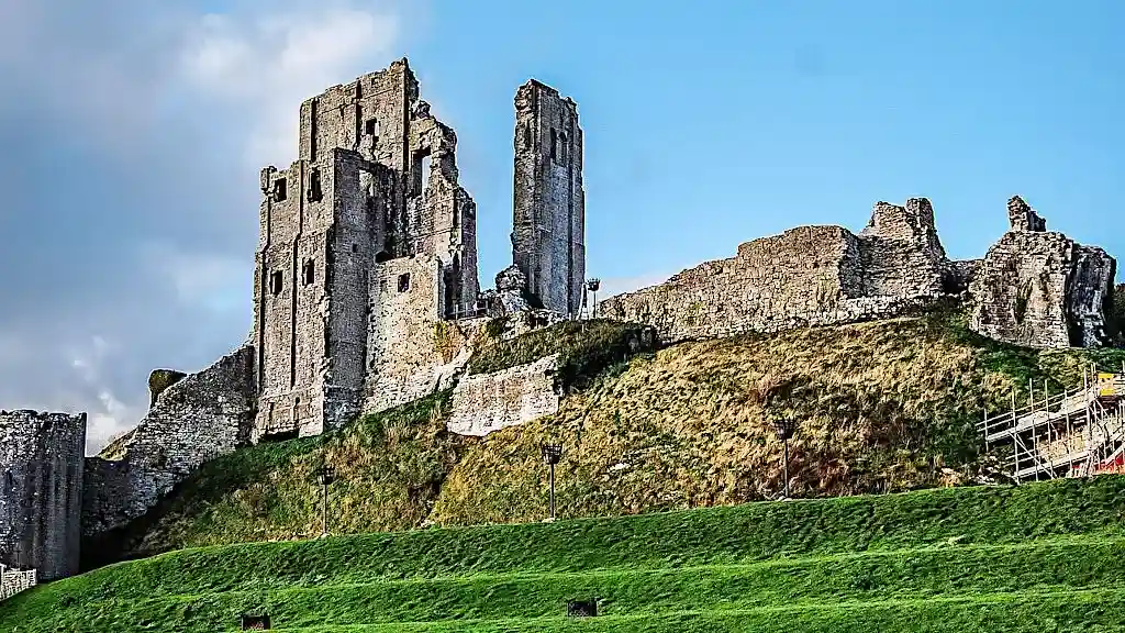 Towering ruins of Corfe Castle. Grey stones and remains of walls on a hill