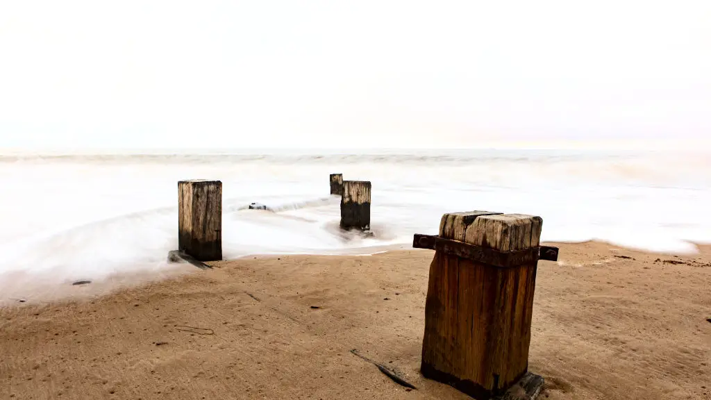 Four wooden beams rise from the sandy beach, washed by the sea