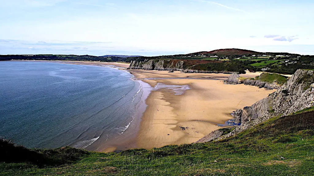 Broad beach cove at Gower Peninsula with grey cliffs and golden sand