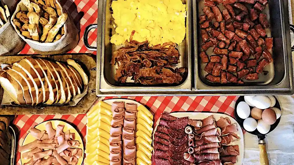 English all inclusive breakfast with plates of bread, ham, sausage, and eggs on chequered tablecloth