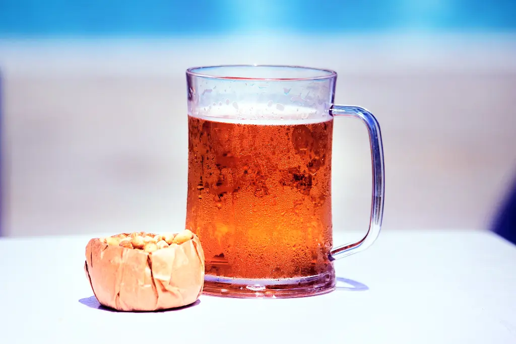 Mug of beer on a table besides some peanuts