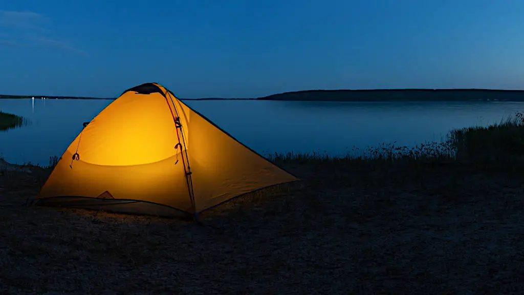 Orange illuminated tent on lake in the evening