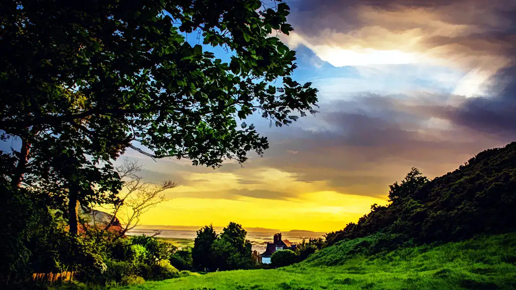 Sunset over a little white cottage with green lawn and the sea as backdrop